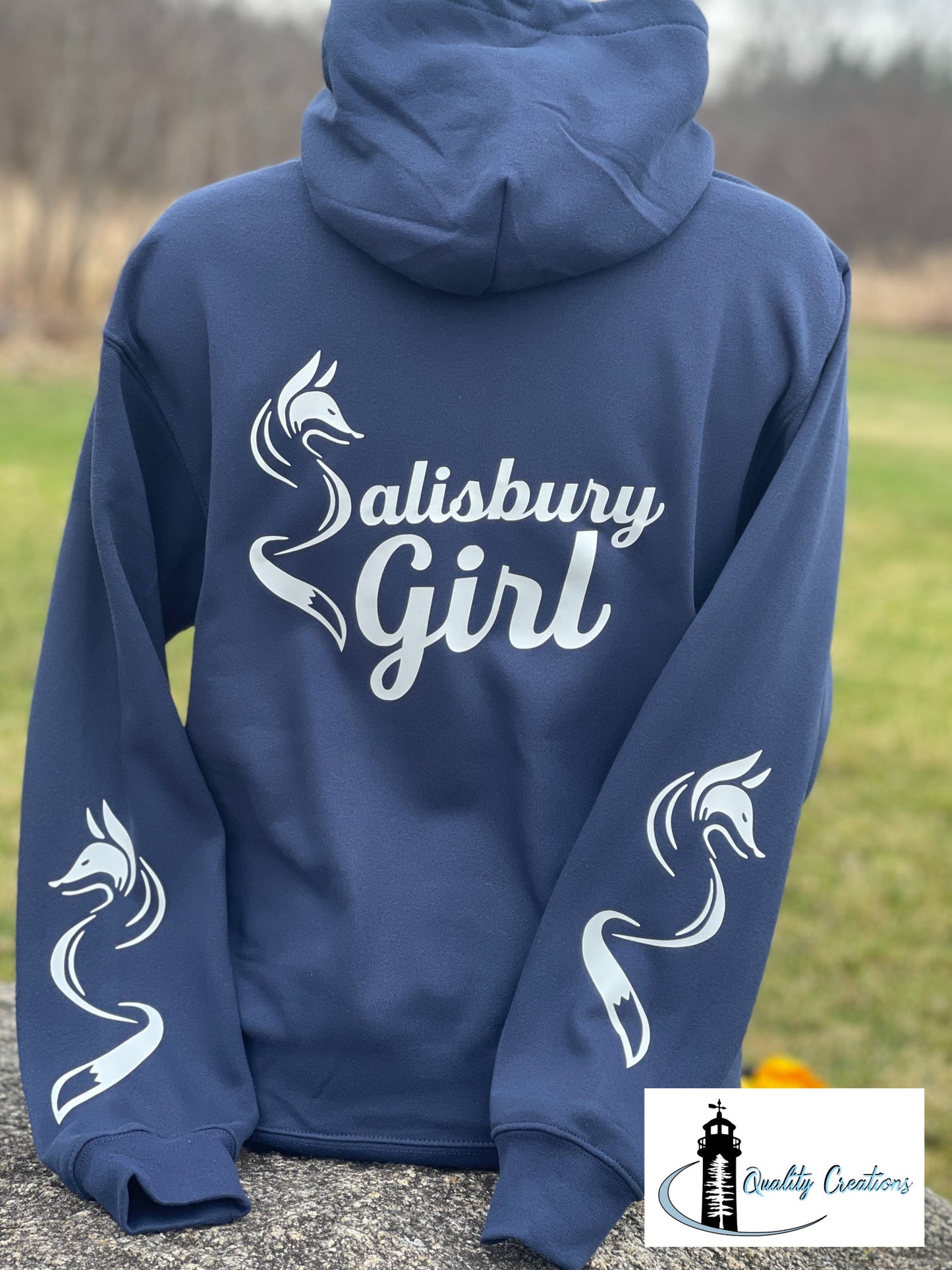 Royal blue Salisbury Girl pullover hoodie with white text and fox graphics on both sleeves. Locally made in Salisbury, New Brunswick—the home of the Silver Fox.