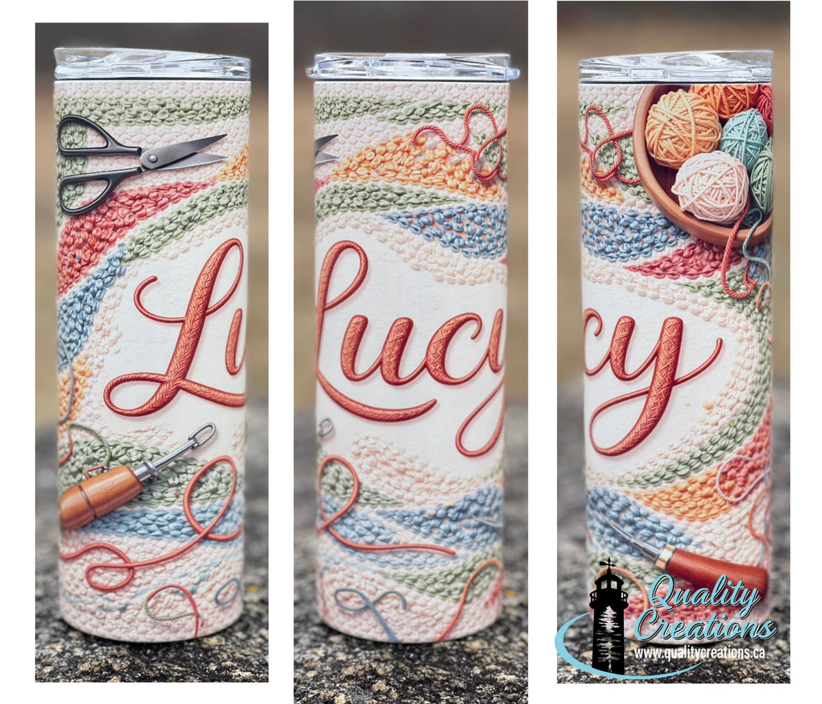 Three views of a clear lidded screw tumbler with a wraparound design featuring the word 'Lucy' in red script over a knitted multicolor pattern, with crochet tools and yarn balls as accents. A 'Quality Creations' watermark is visible on the right view.