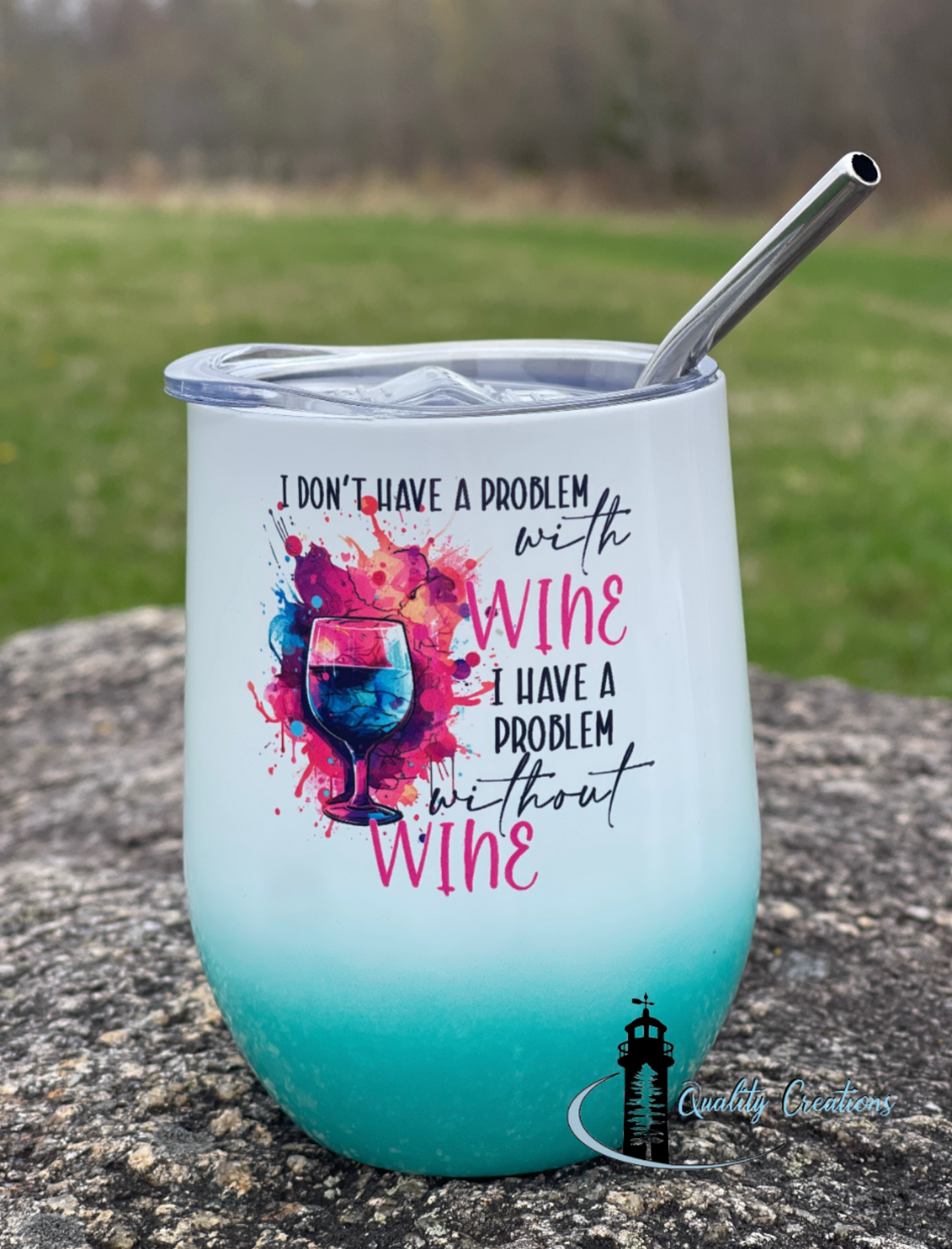 Turquoise wine tumbler with colorful design and text on a stone surface.