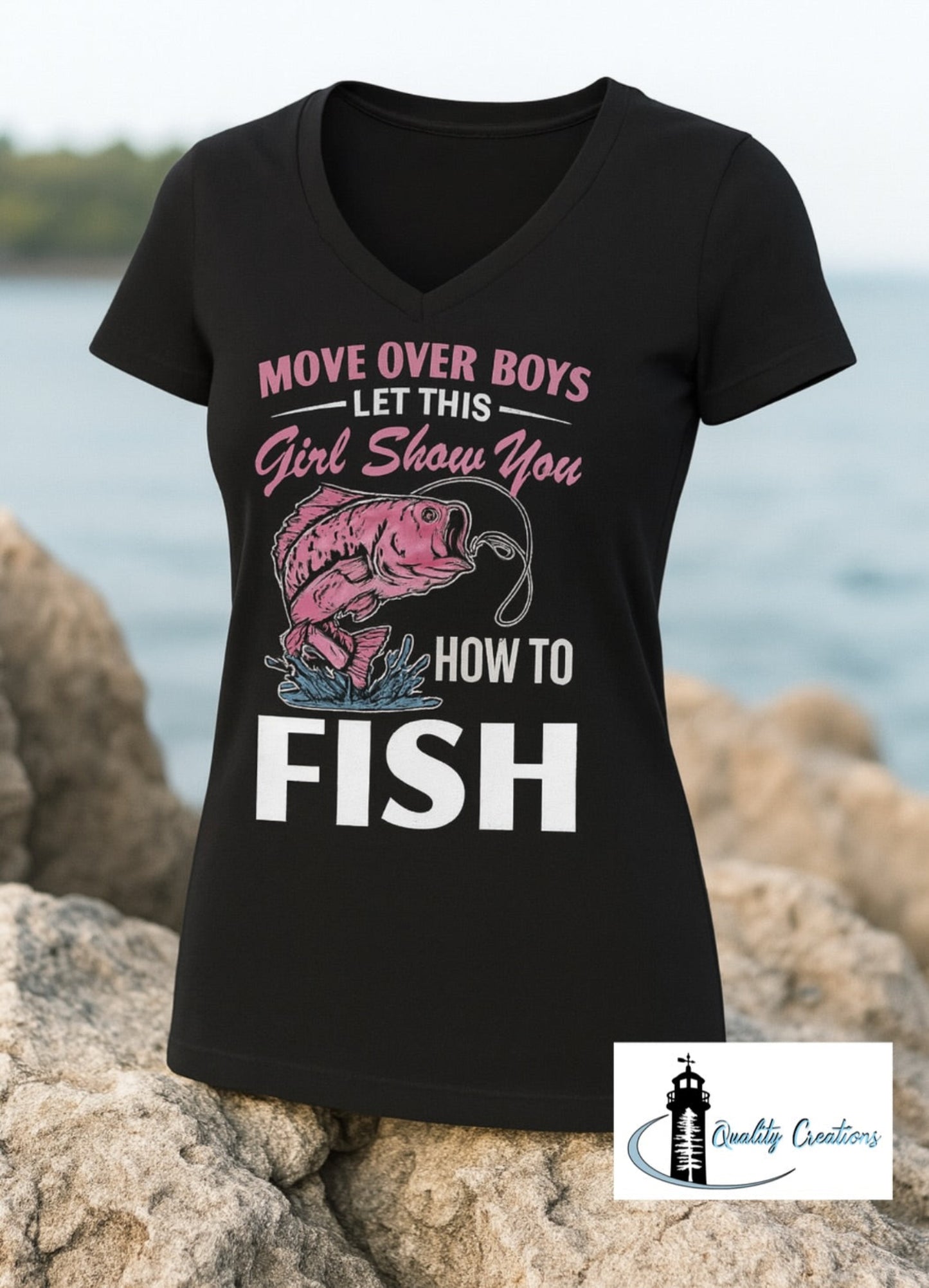 Black women's V-neck fishing shirt with pink graphic text that says "Move Over Boys, Let This Girl Show You How to Fish" – displayed on rocks by the water Located in Salisbury near Moncton New Brunswick