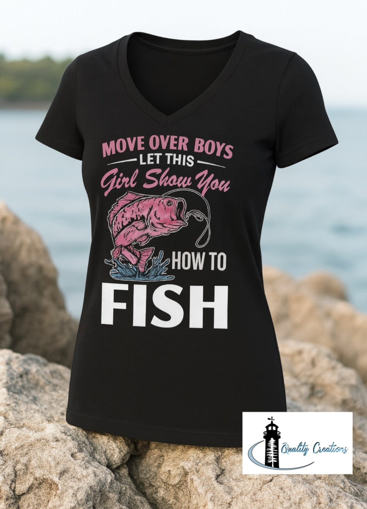 Black women's V-neck fishing shirt with pink graphic text that says "Move Over Boys, Let This Girl Show You How to Fish" – displayed on rocks by the water Located in Salisbury near Moncton New Brunswick