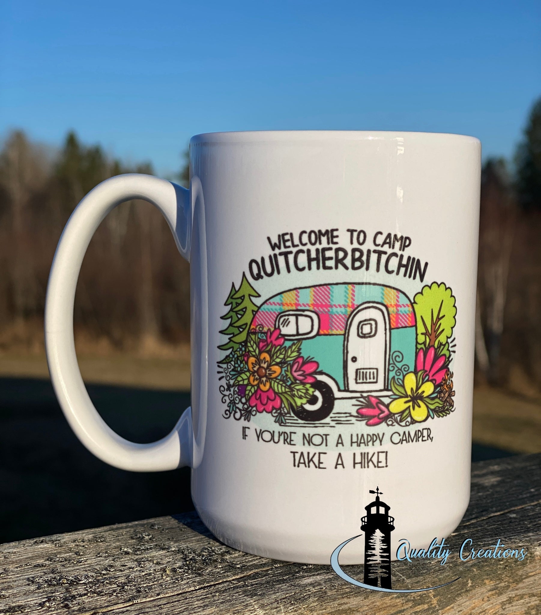 Quitcherbitchin 15 oz camping mug with colourful trailer design – photographed outdoors on picnic table in New Brunswick