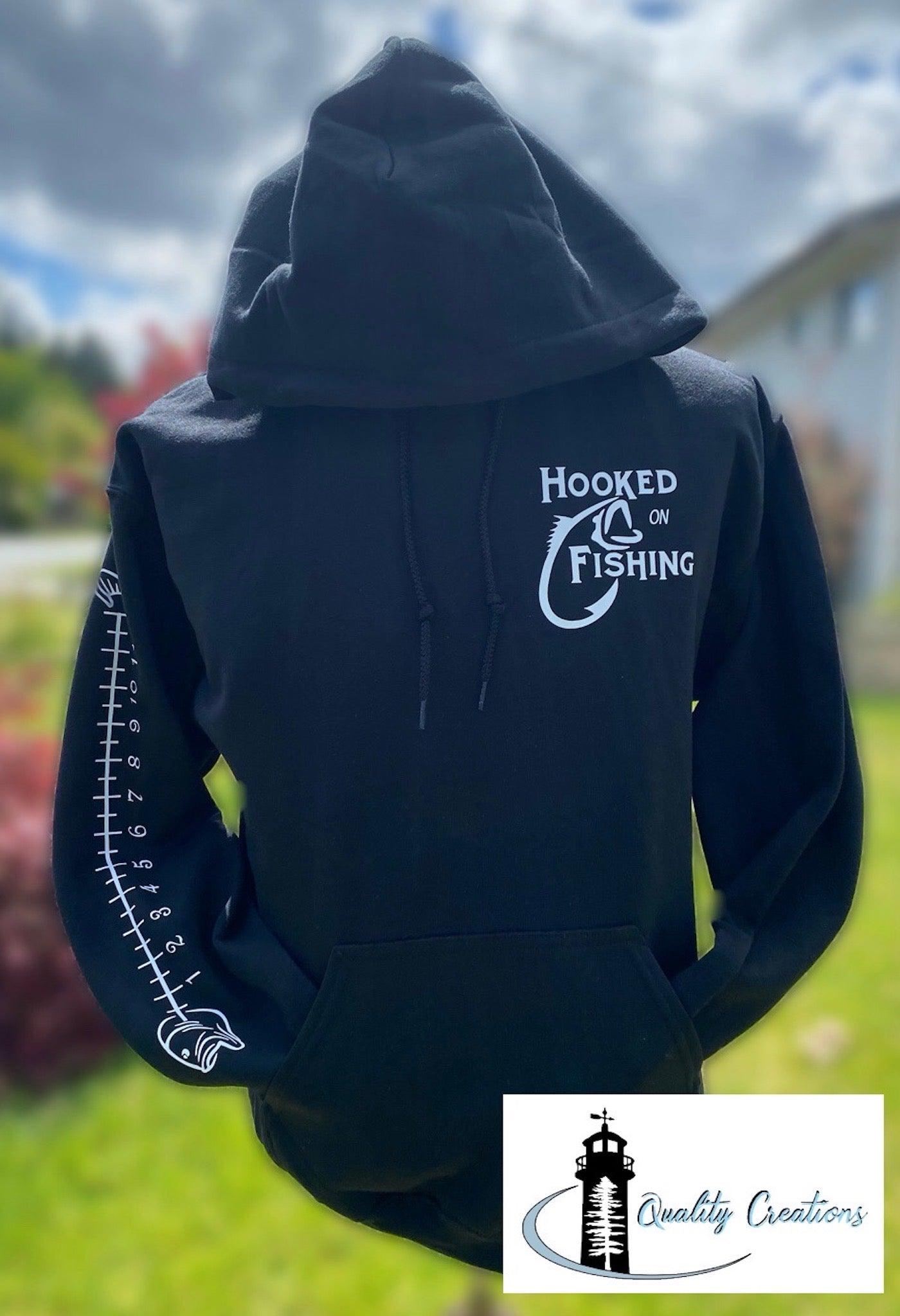 fish measuring on arm with white font on front with hooked on fishing quality creations canada